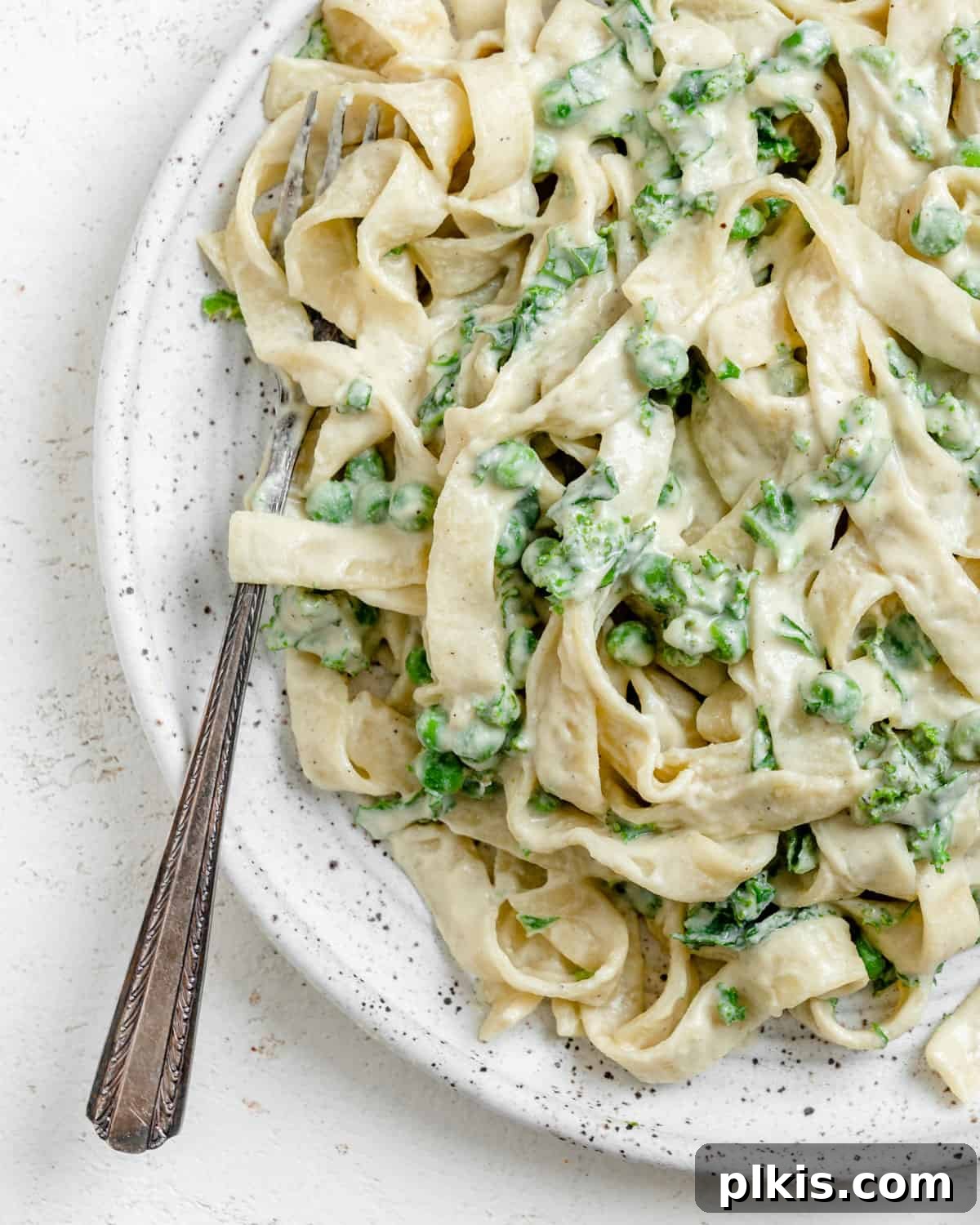Green Goodness Alfredo 2 completed Dairy Free Alfredo Sauce with Kale and Peas plated on a white plate against a white surface