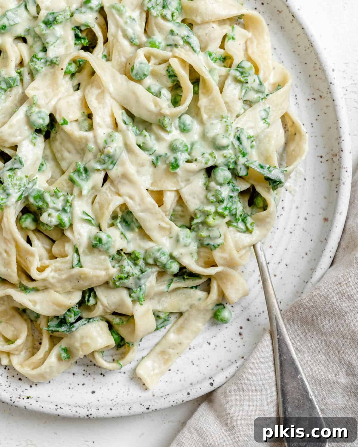 Green Goodness Alfredo 7 completed Dairy Free Alfredo Sauce with Kale and Peas plated on a white plate against a white surface