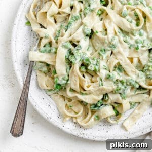 Green Goodness Alfredo 8 completed Dairy Free Alfredo Sauce with Kale and Peas plated on a white plate against a white surface