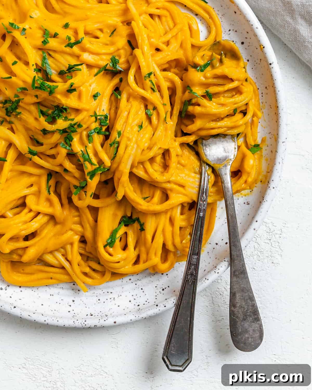 Velvety Sweet Potato Spaghetti 2 Completed Sweet Potato Pasta Sauce with Spaghetti plated against a white surface, garnished with fresh herbs