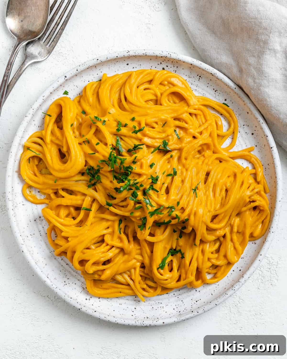 Velvety Sweet Potato Spaghetti 14 Completed Sweet Potato Pasta Sauce with Spaghetti plated against a white surface, garnished beautifully