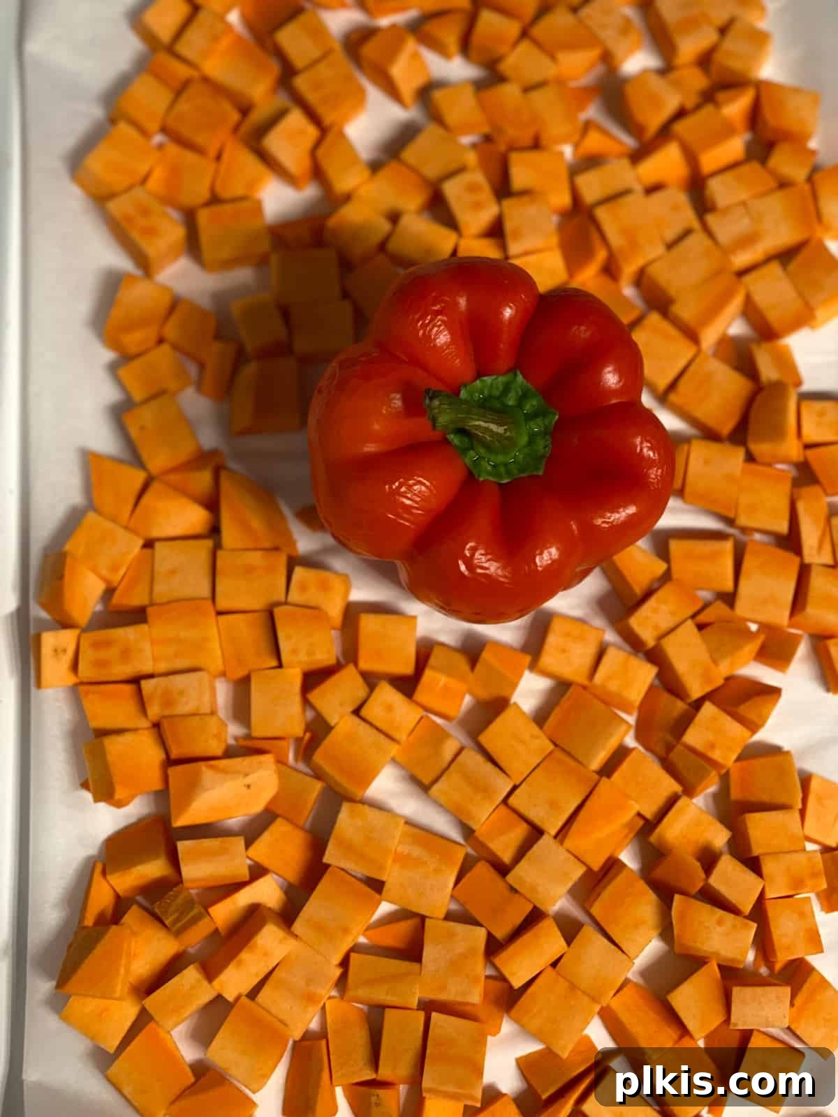 Velvety Sweet Potato Spaghetti 5 Cubed sweet potato alongside a red pepper on a baking tray, ready for the oven