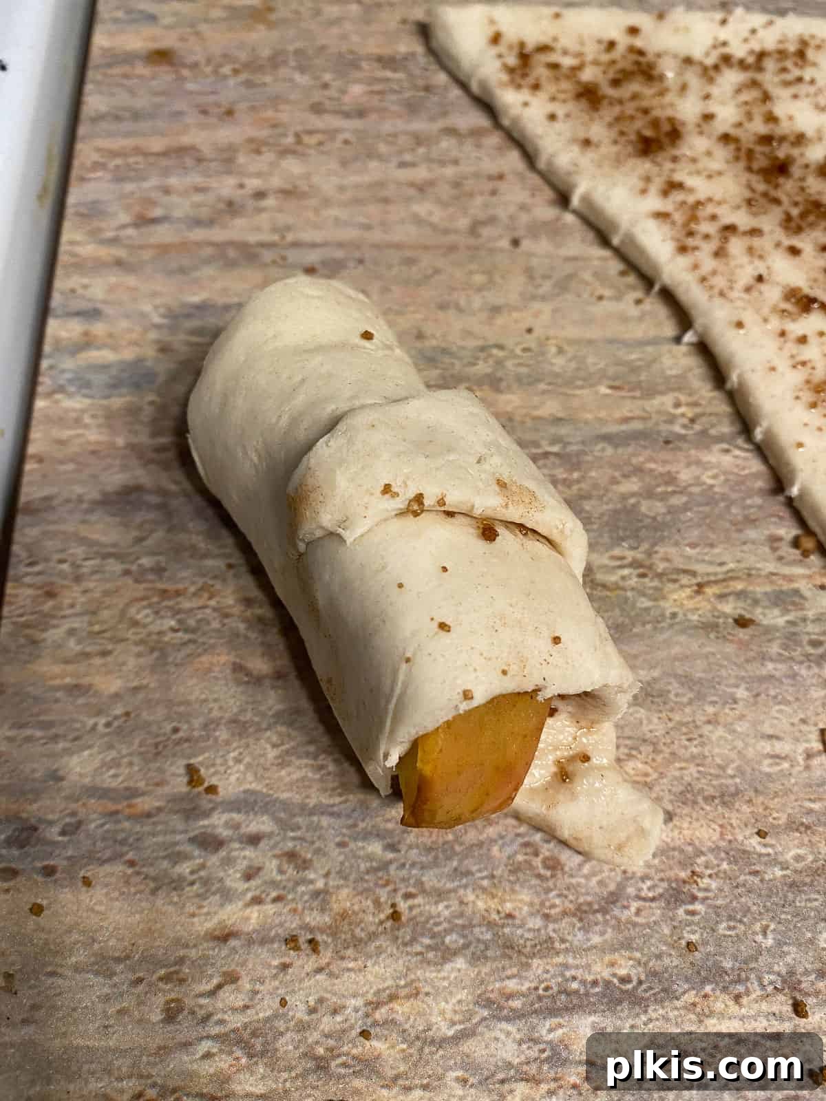 Golden Apple Cinnamon Crescents 12 A rolled apple crescent roll, ready for its final brushing and baking.