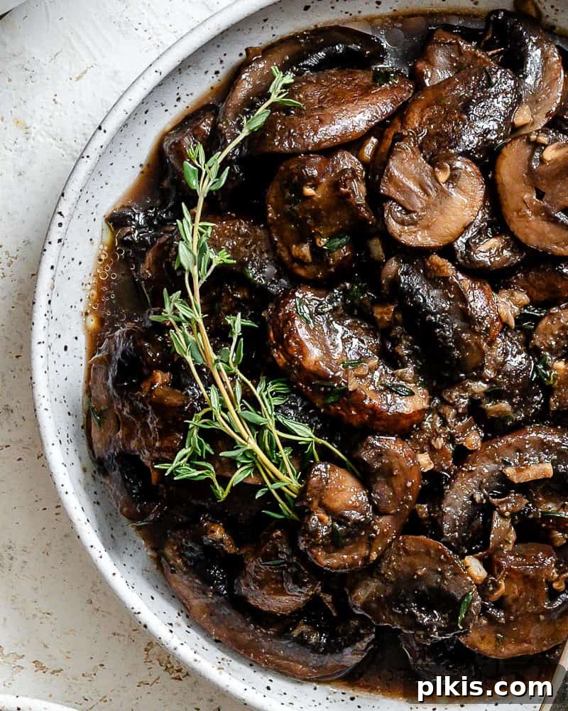 Sizzling Garlic Thyme Mushrooms 10 completed Sauteed Mushrooms with Garlic and Thyme on a white surface, close up