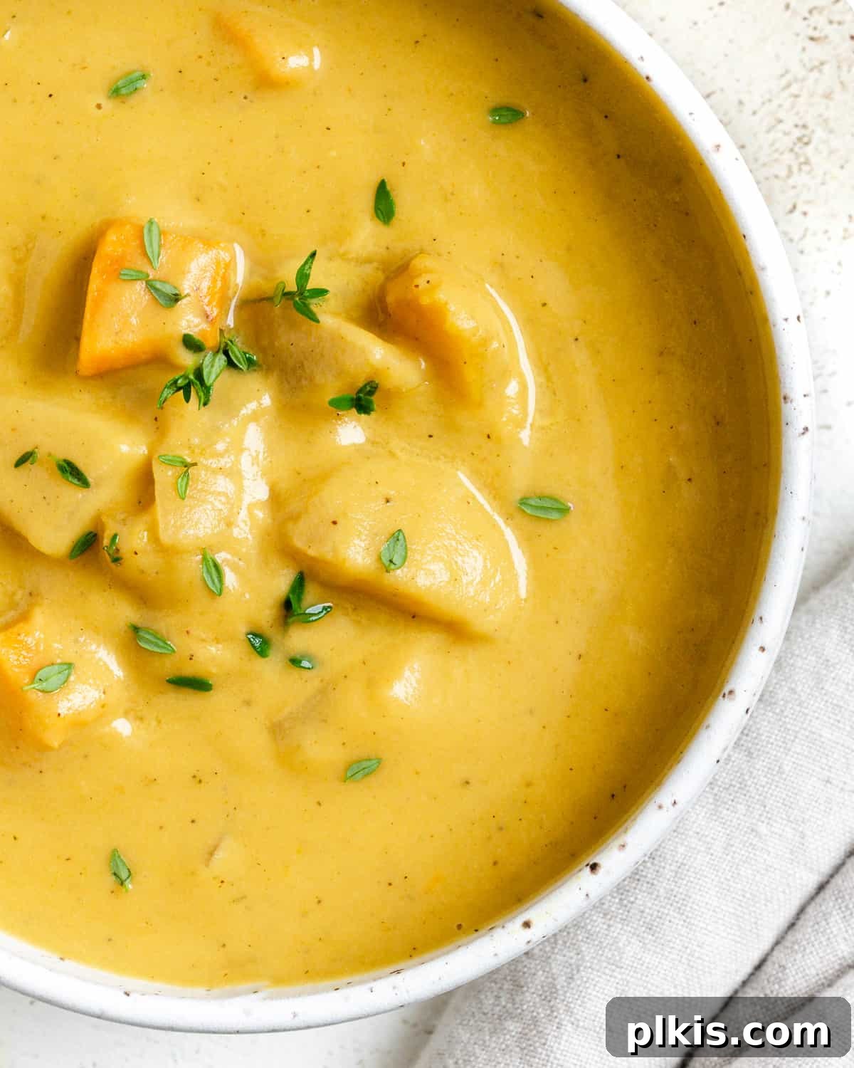 Golden Roasted Delicata Sweet Potato Soup 2 Completed Roasted Delicata Squash and Sweet Potato Soup in a white bowl against a light background, garnished with fresh herbs