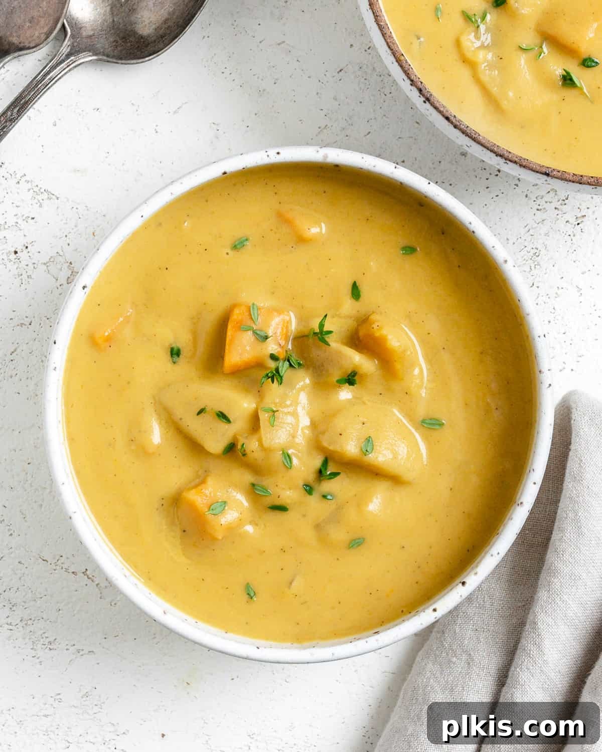 Golden Roasted Delicata Sweet Potato Soup 18 Completed Roasted Delicata Squash and Sweet Potato Soup in a white bowl against a light background, ready to be garnished