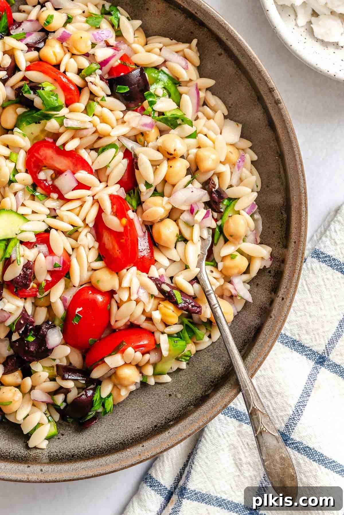 Zesty Lemon Orzo Salad 2 Completed Easy Lemon Orzo Salad in a beautiful serving bowl, showcasing its vibrant colors and fresh ingredients like cherry tomatoes, cucumbers, red onion, and chickpeas, all coated in a zesty dressing.