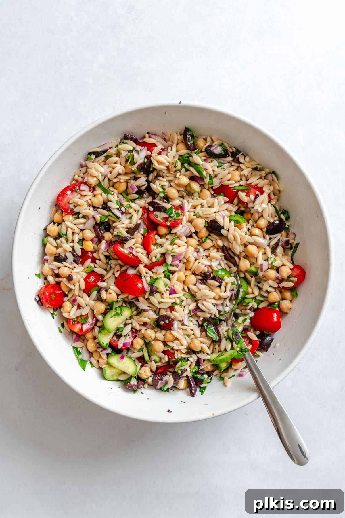 Zesty Lemon Orzo Salad 7 Process shot showing the Lemon Orzo Salad fully mixed in a large bowl, with all ingredients evenly coated in the dressing, ready for chilling and serving.