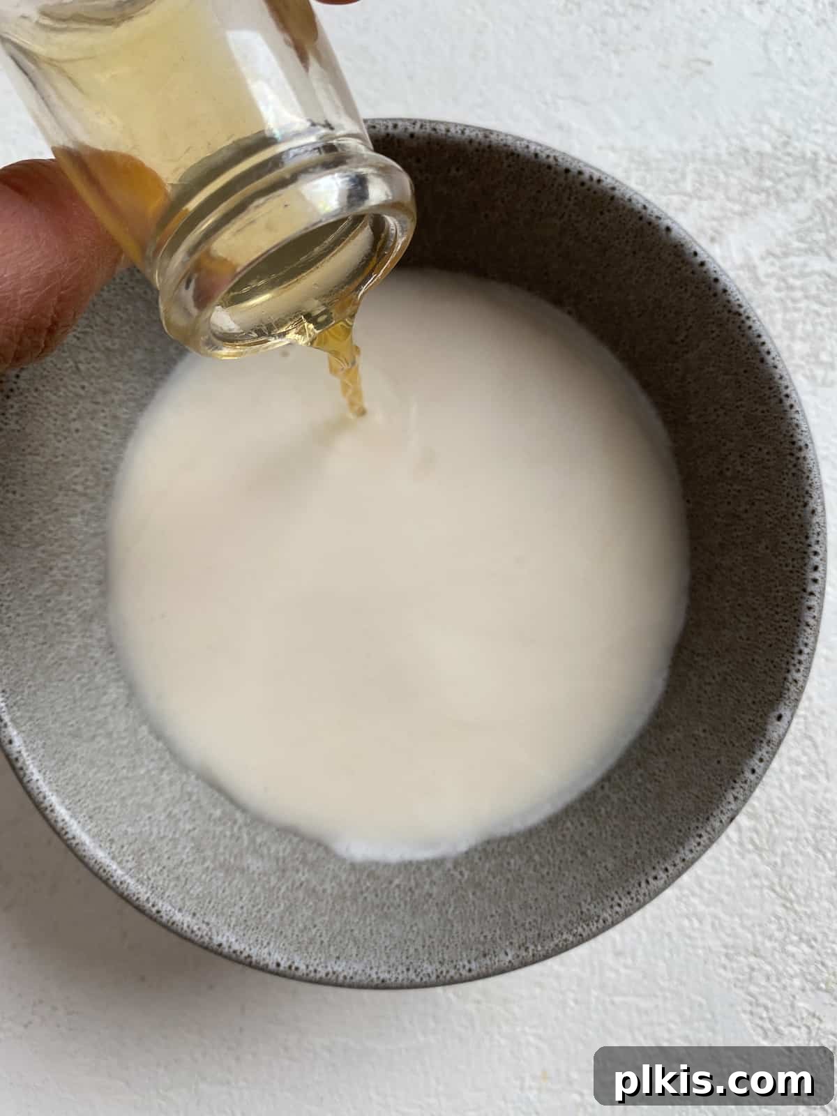 Golden Sage Butternut Biscuits 4 Plant-based milk being combined with apple cider vinegar in a small bowl to create a buttermilk substitute.