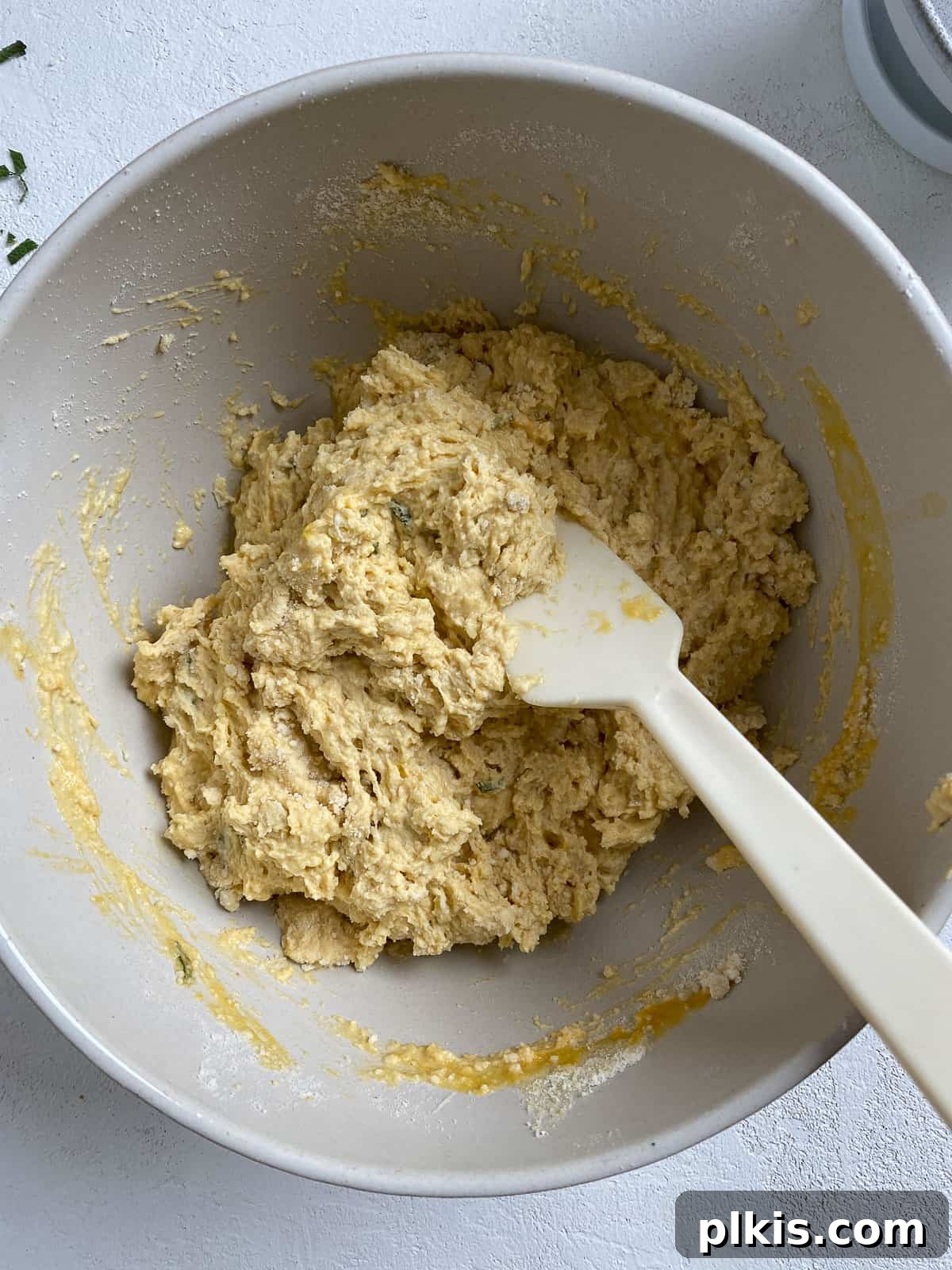 Golden Sage Butternut Biscuits 8 Wet ingredients being gently mixed into the dry ingredients for Butternut Squash Sage Biscuits, forming a cohesive dough.