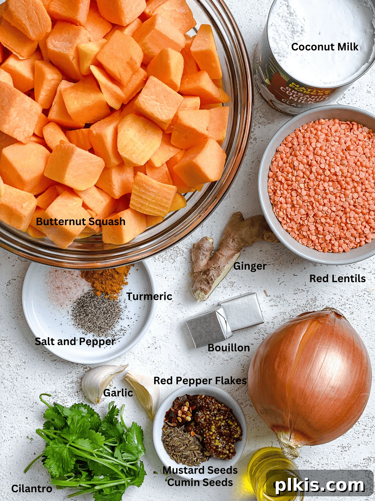 Hearty Butternut Squash and Lentil Soup 3 Various fresh ingredients for butternut squash and lentil soup, including diced squash, lentils, onions, garlic, and spices, neatly arranged on a white surface.