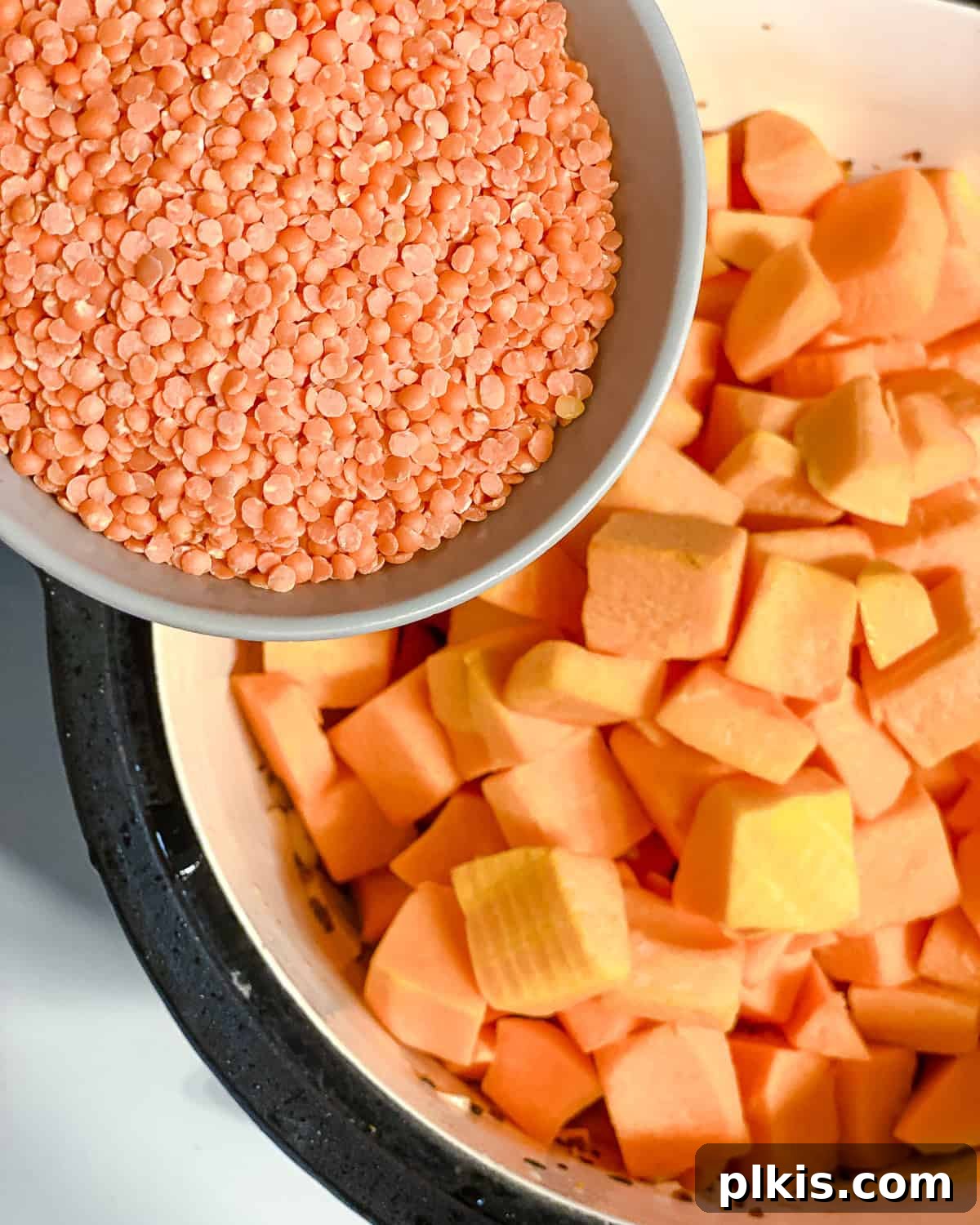 Hearty Butternut Squash and Lentil Soup 6 Process shot of adding dry red lentils to a pot with sautéed aromatics and spices.