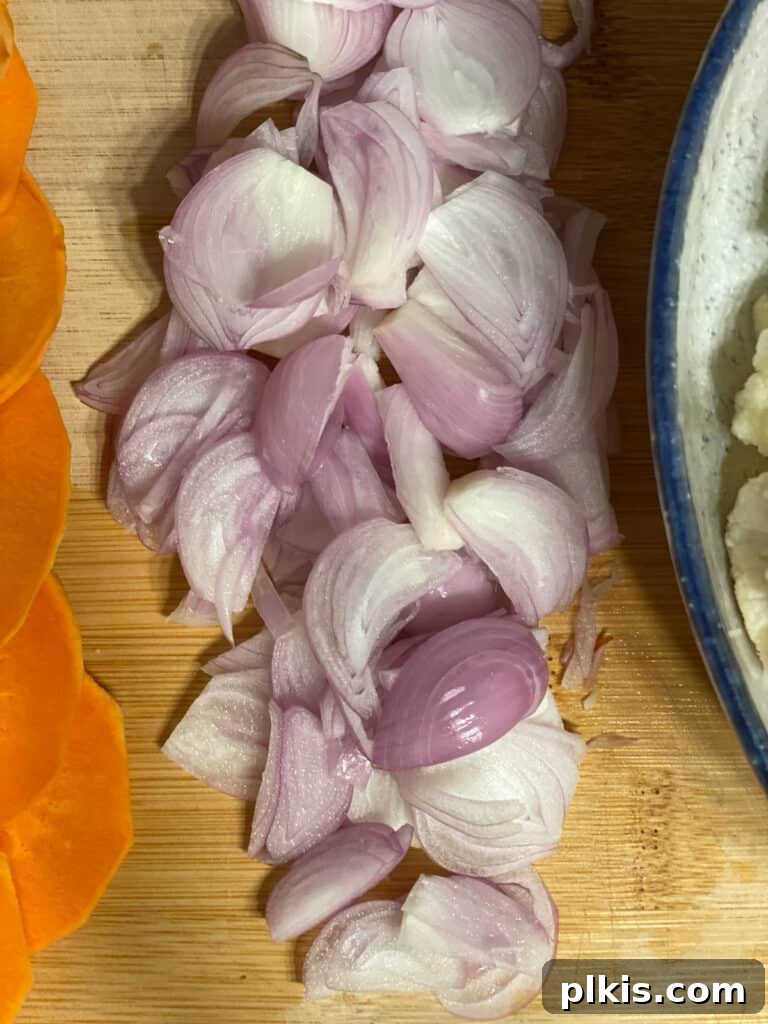 Close-up of finely chopped shallots on a wooden cutting board, ready to be incorporated into the casserole layers.
