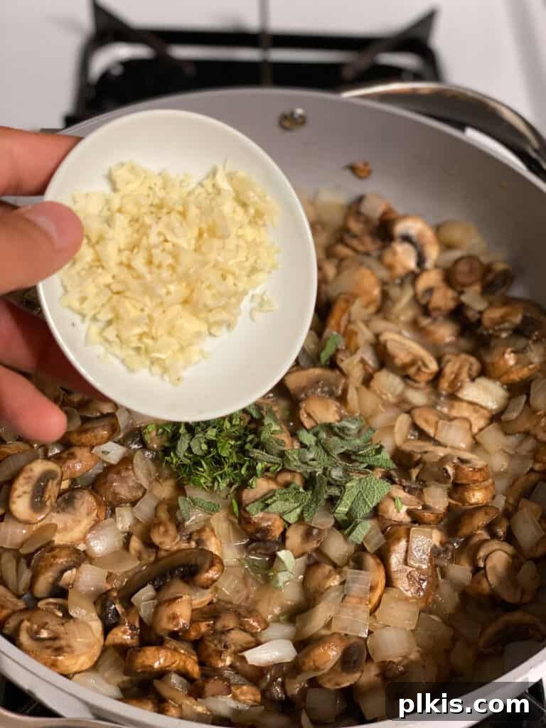 Minced garlic cloves being added to the pan, intensifying the aromatic base of the mushroom gravy.