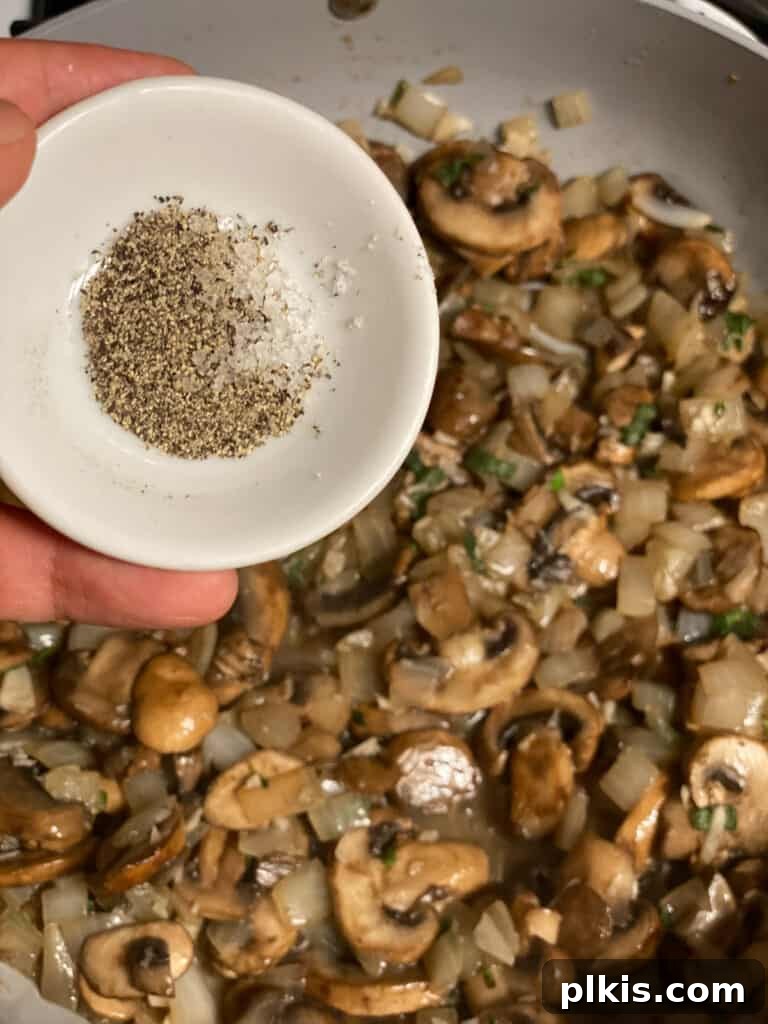 Salt and freshly ground black pepper being sprinkled into the pan, seasoning the gravy mixture.