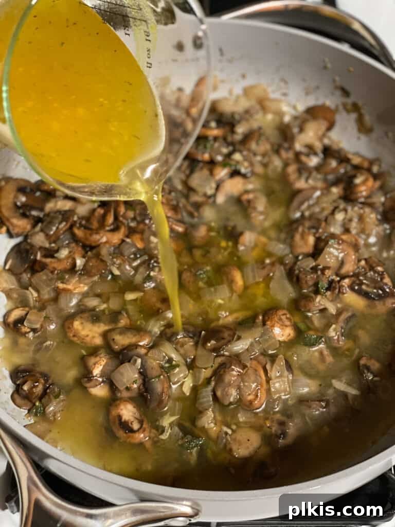 Vegetable broth being poured into the pan with the sautéed ingredients, forming the liquid base of the gravy.