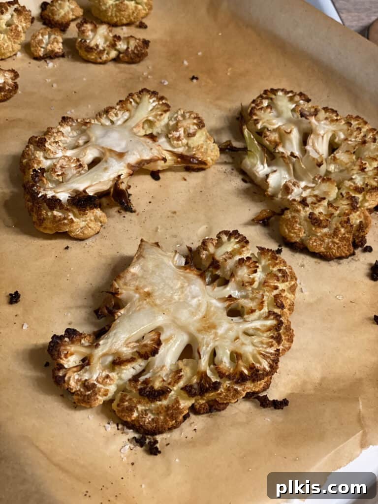 Crispy roasted cauliflower steaks with golden-brown edges, served fresh from the oven, showcasing their perfect texture.