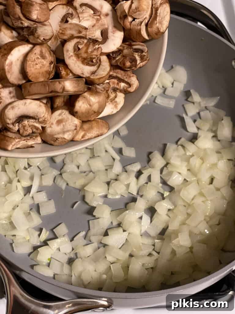 Sliced mushrooms being added to the pan with sautéed onions, ready to cook down for the gravy.