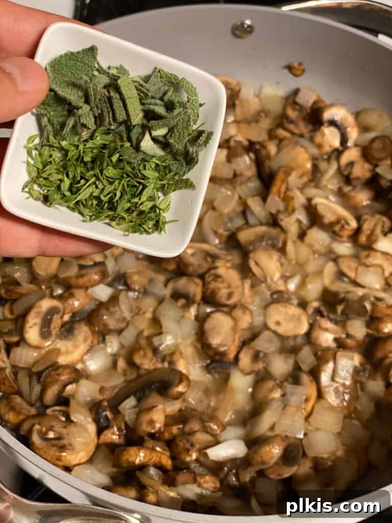 Fresh sage leaves being added to the sautéing vegetables in the pan, infusing the gravy with its distinct aroma.