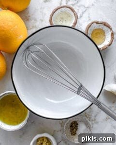 ingredients for lemon dressing placed around a white bowl and whisk