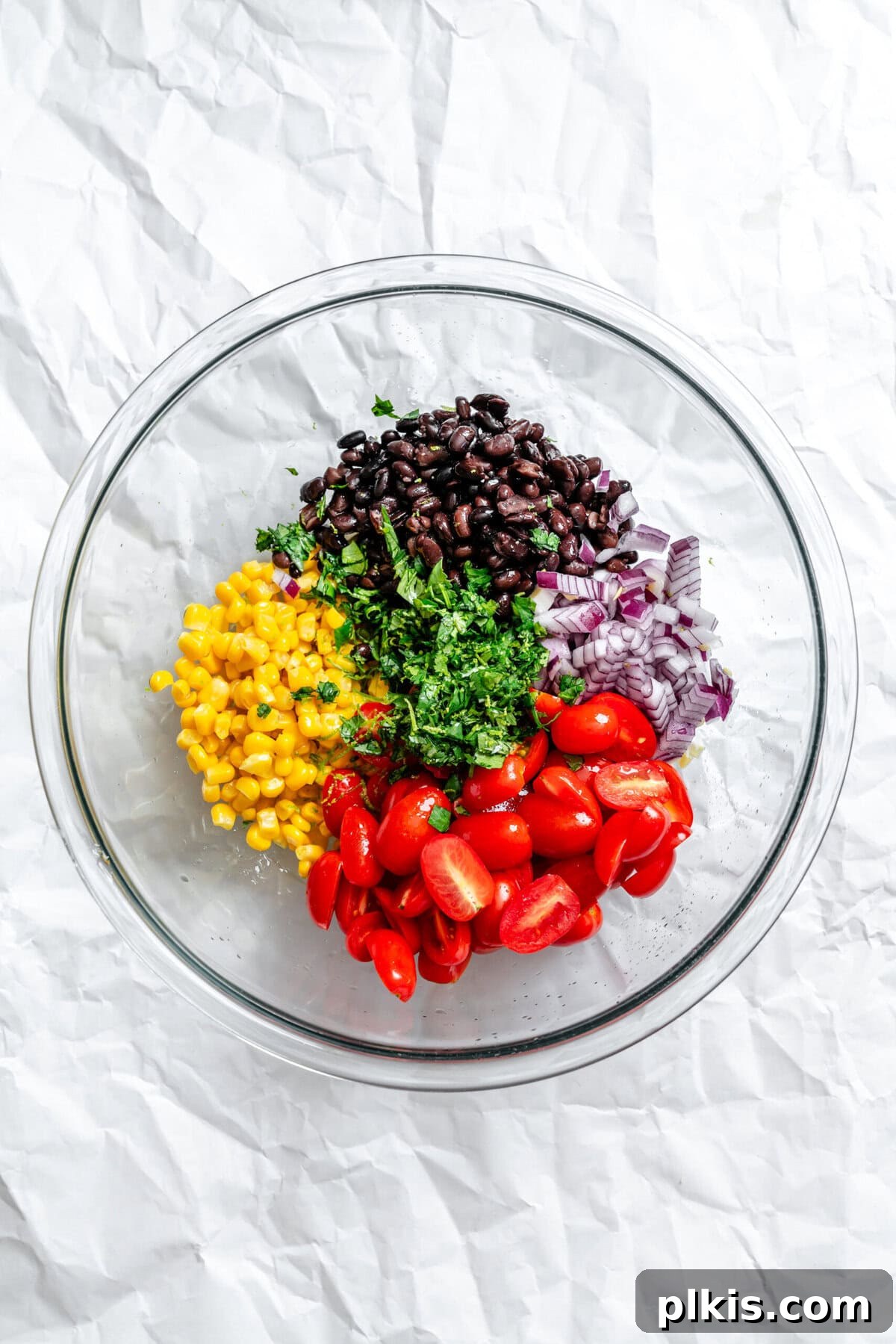 Southwestern Quinoa and Black Bean Fiesta 5 Process shot showing mixed salad ingredients (black beans, corn, red onion, tomatoes, cilantro) in a large bowl.