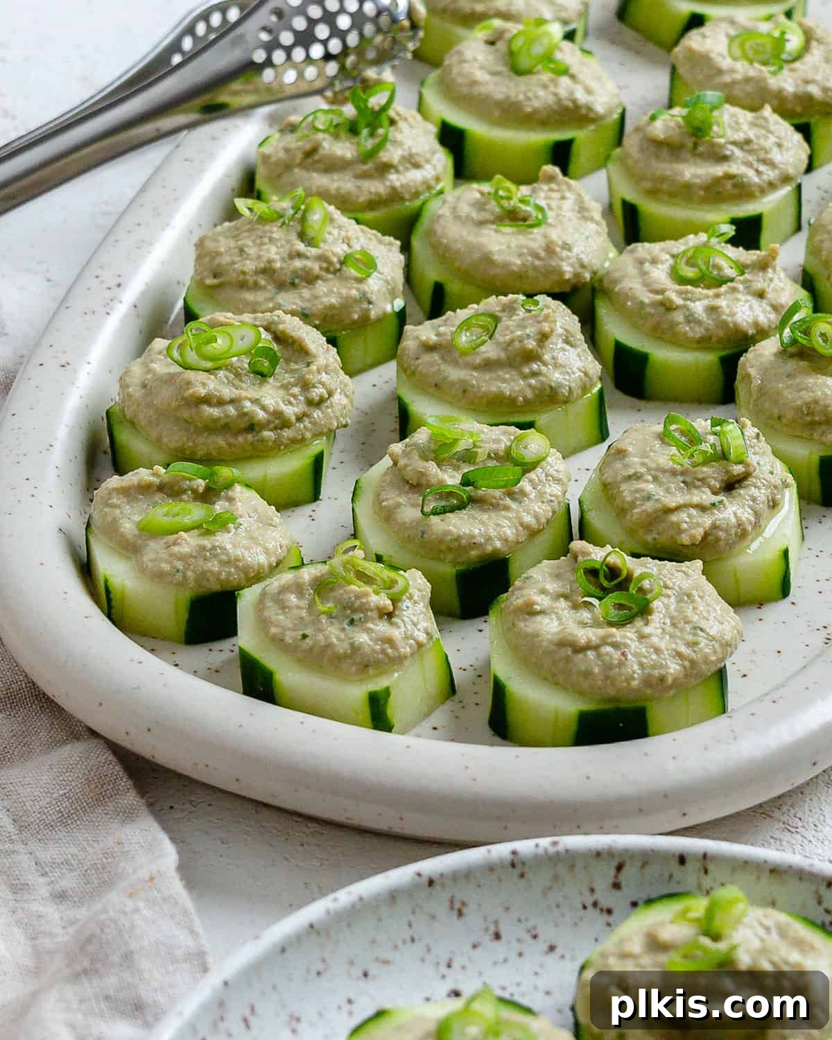 Refreshing Cucumber & Chive Sunflower Cream Bites 8 Completed Easy Cucumber Bites with Sunflower Chive Cream Cheese arranged neatly on a serving platter, garnished with fresh chives, ready to be enjoyed.