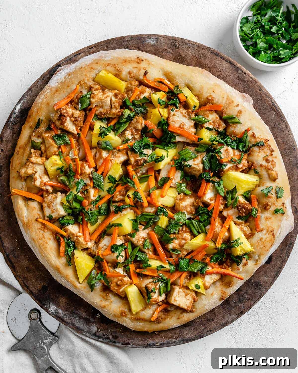 Irresistible Vegan Thai Pizza 2 completed shot of Thai pizza post being baked on brown and white surface