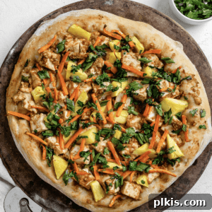 completed shot of Thai pizza post being baked on brown and white surface with a slice cut out