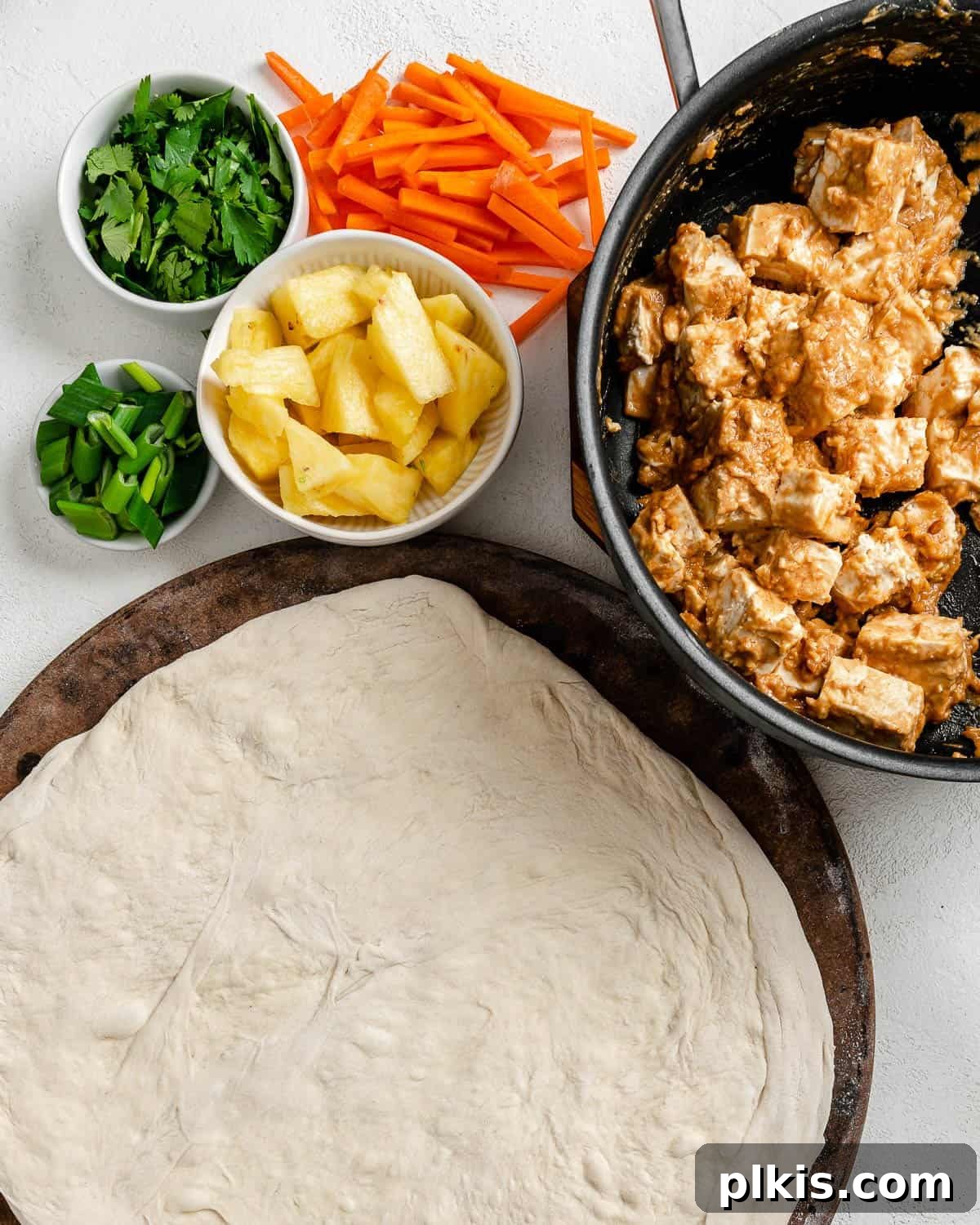 Irresistible Vegan Thai Pizza 8 marinated tofu in a bowl alongside separate bowls of veggies and pizza dough