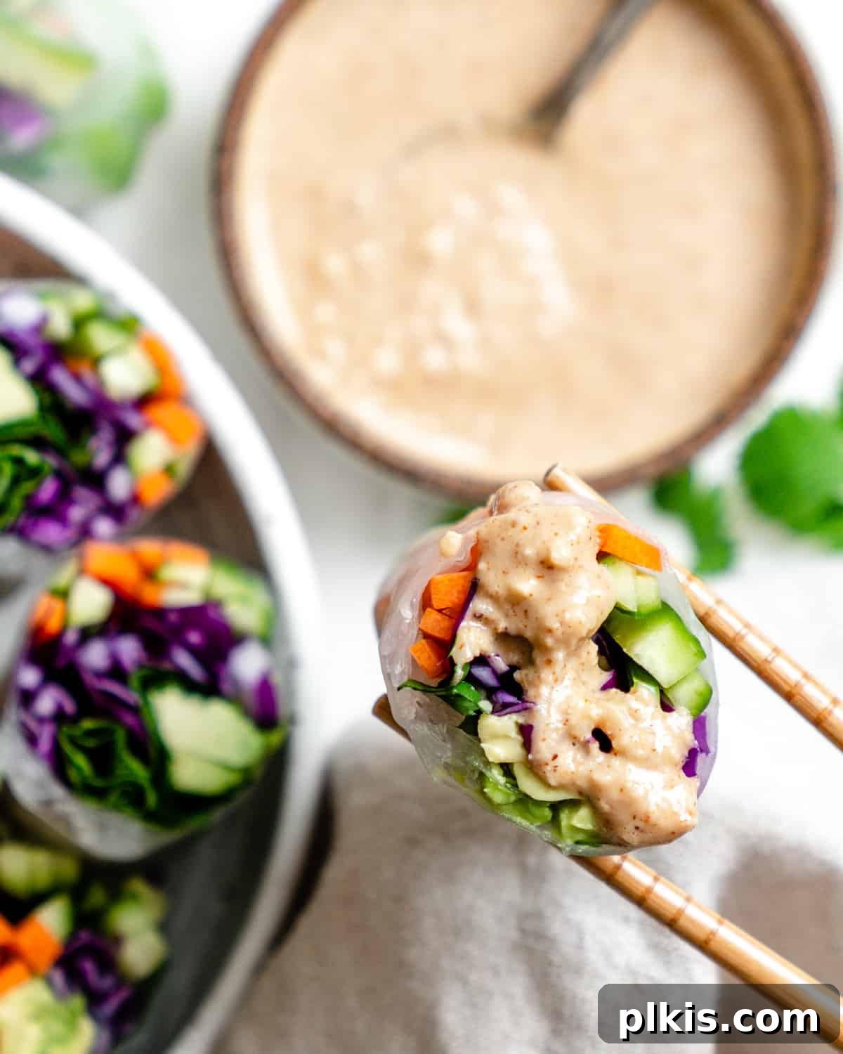 Vibrant Rainbow Rolls with Creamy Almond Shallot Dip 11 A close-up shot of several completed Fresh Rainbow Rolls with Almond Shallot Sauce in a serving bowl, highlighting the intricate layers of colorful vegetables.