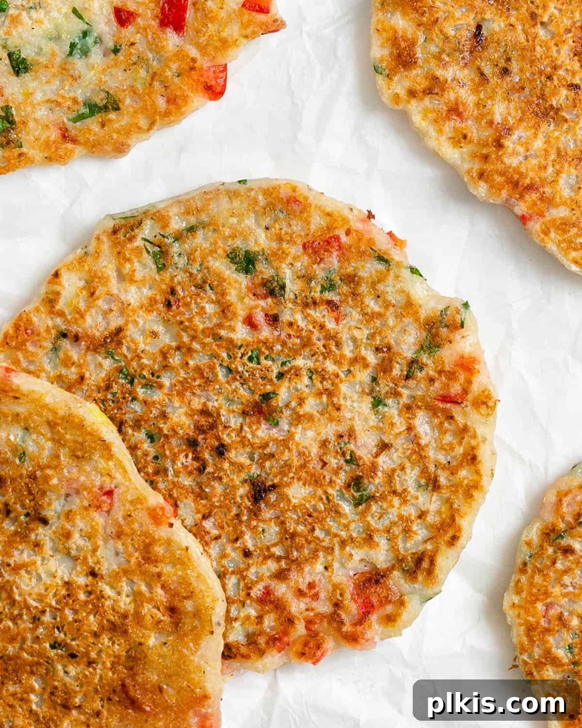 Crispy Vegan Potato Pancakes 2 Golden brown vegan potato pancakes stacked on a white plate, garnished with fresh herbs, ready to be enjoyed.