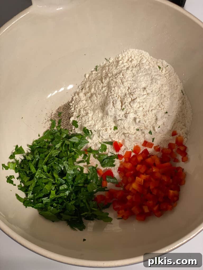 Crispy Vegan Potato Pancakes 5 Dry ingredients and chopped vegetables being mixed together in a bowl with a spoon.