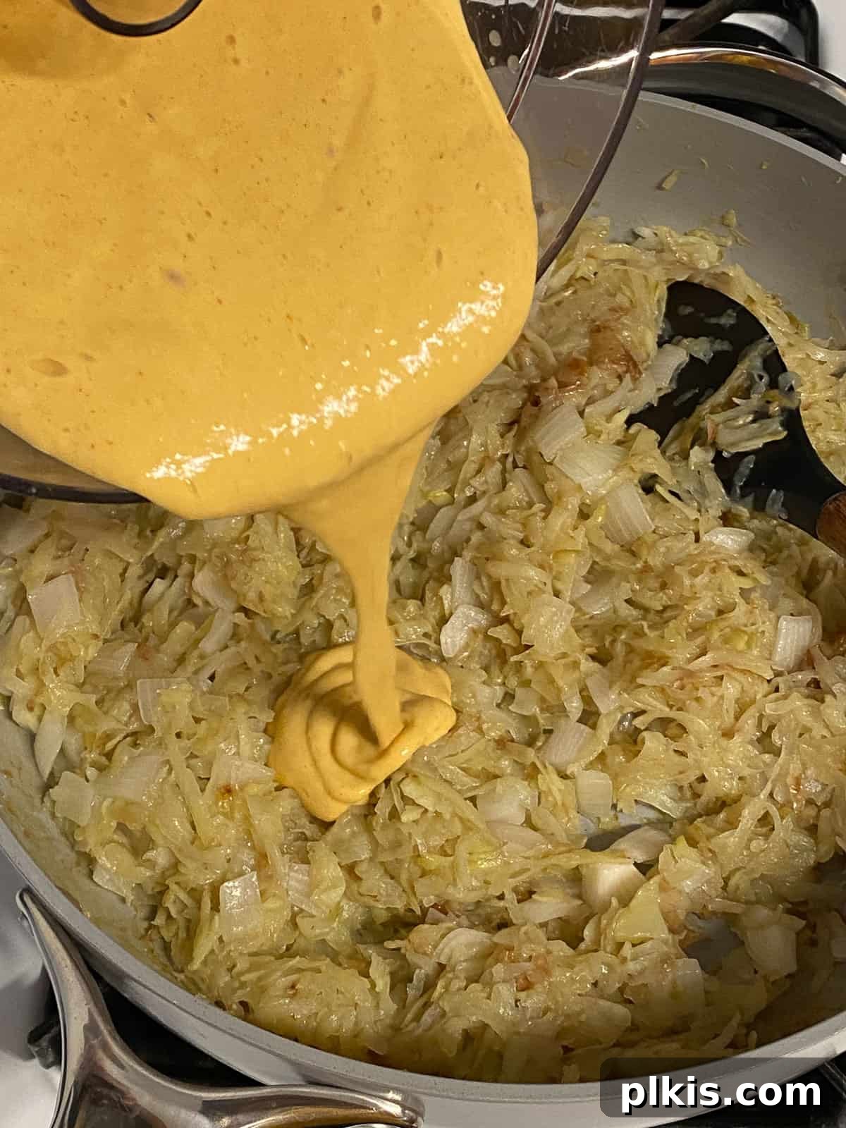 Further process shot of adding blended mixture to potato mixture in pan, ensuring a thorough mix for the vegan frittata.