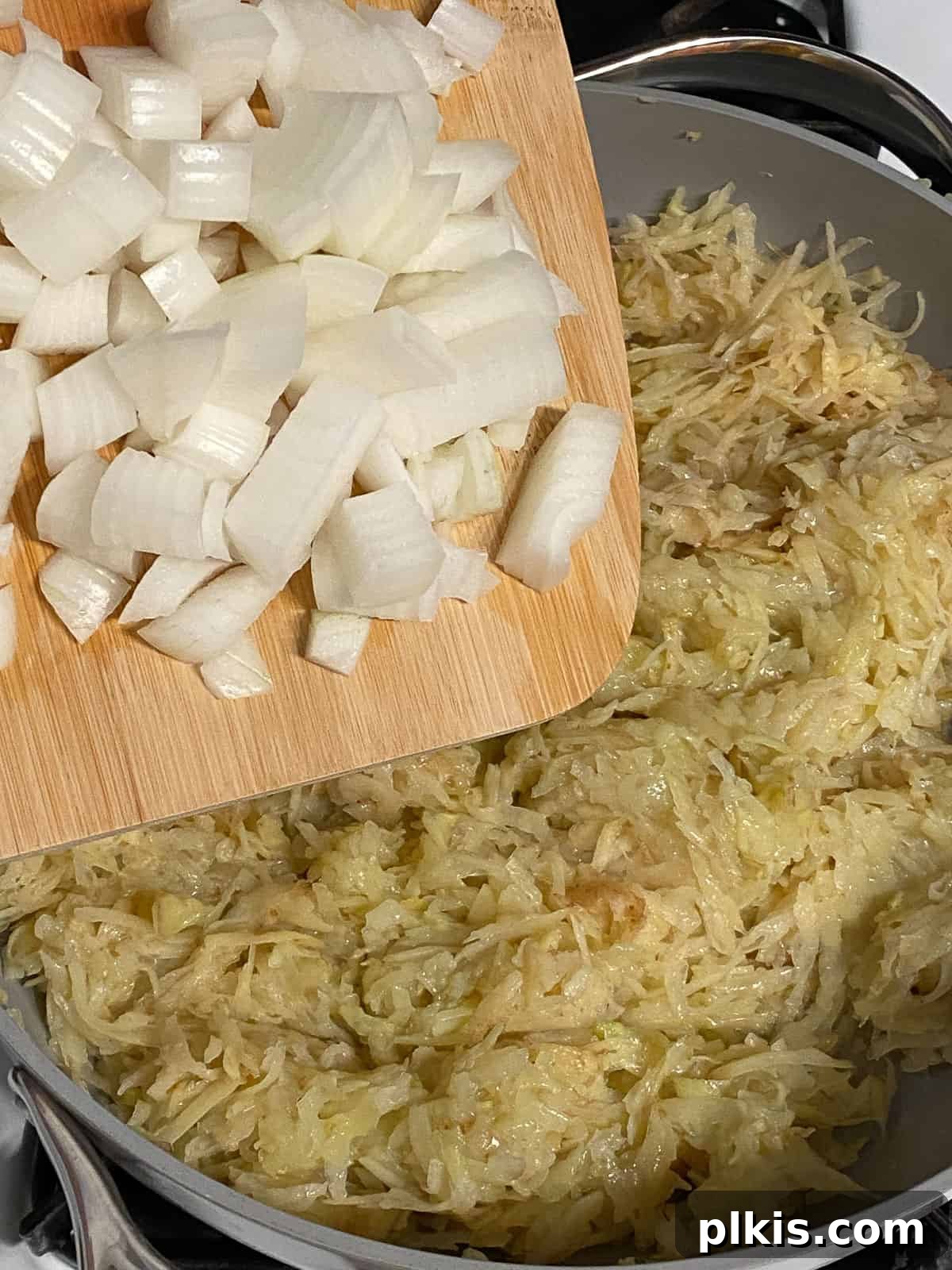 Process shot of adding diced onions to a pan with potatoes, showing the step of sautéing aromatics for the vegan frittata.
