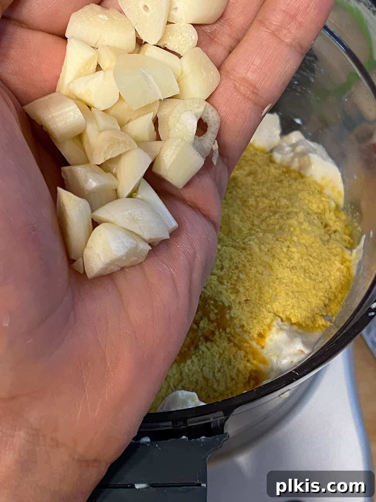 Process shot of adding garlic to a blender, contributing essential aromatics to the vegan frittata mixture.