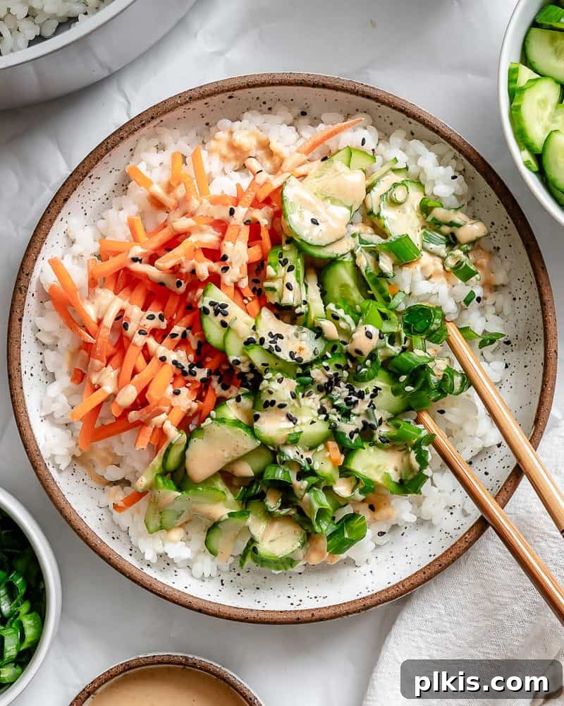 Unrolled Sushi 2 A vibrant vegan sushi bowl brimming with seasoned sushi rice, colorful vegetables like carrots and cucumbers, pan-fried tofu, and a generous drizzle of spicy mayo, garnished with nori strips and sesame seeds.