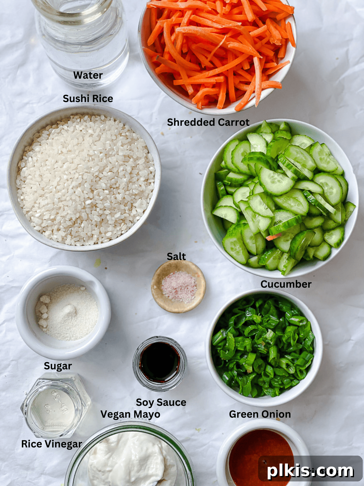 Unrolled Sushi 3 Individual bowls showcasing the essential ingredients for a vegan sushi bowl: cooked sushi rice, fresh shredded carrots, sliced cucumbers, chopped green onions, and the components for spicy vegan mayo.