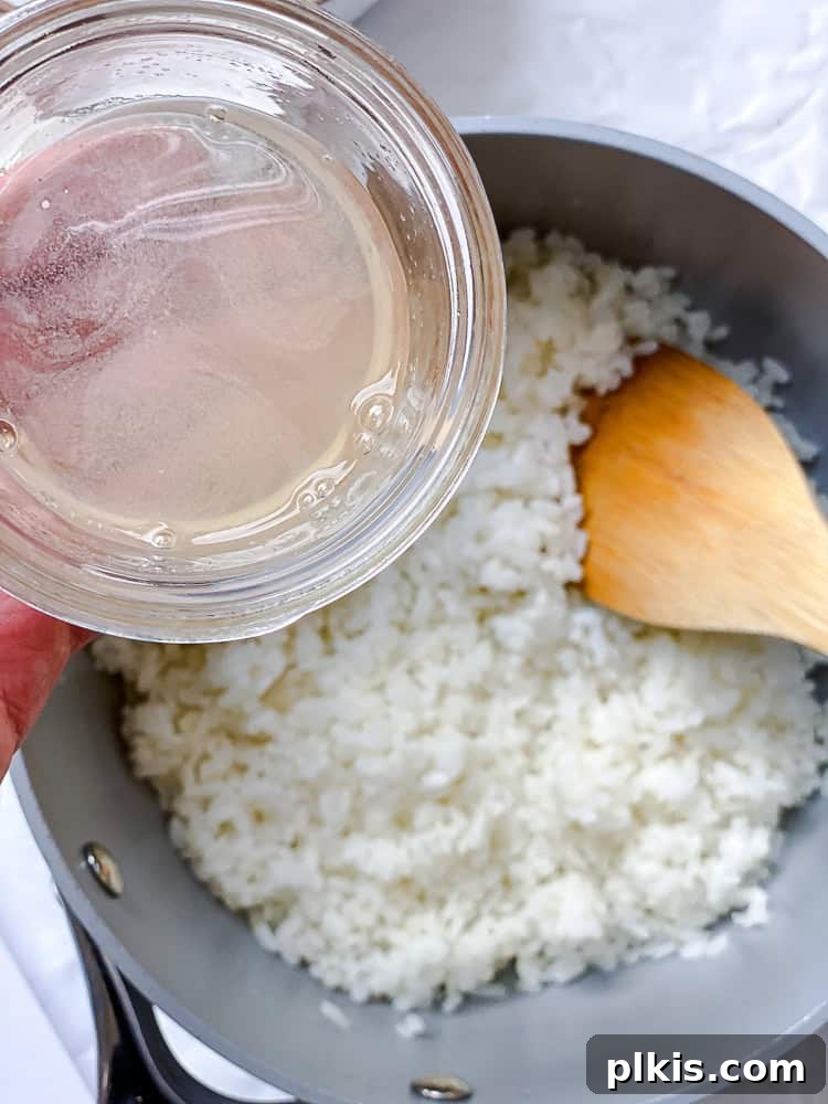 Unrolled Sushi 6 Cooked sushi rice being gently seasoned with a rice vinegar mixture in a large bowl.