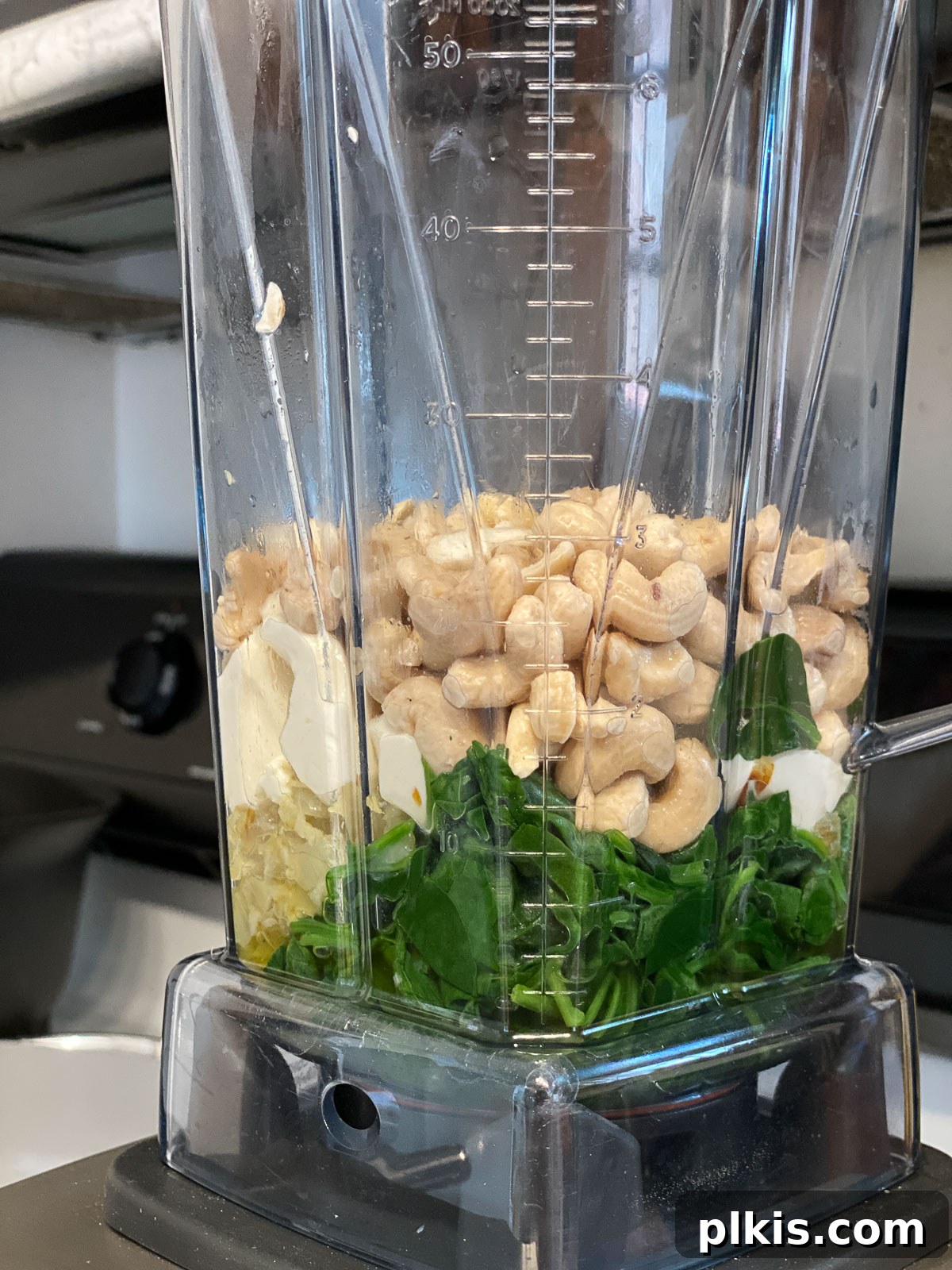 Dreamy Vegan Spinach Dip 10 A blender filled with all the vibrant green ingredients for vegan spinach dip, before blending, showcasing the raw cashews, spinach, tofu, and aromatics ready to be processed into a smooth dip.