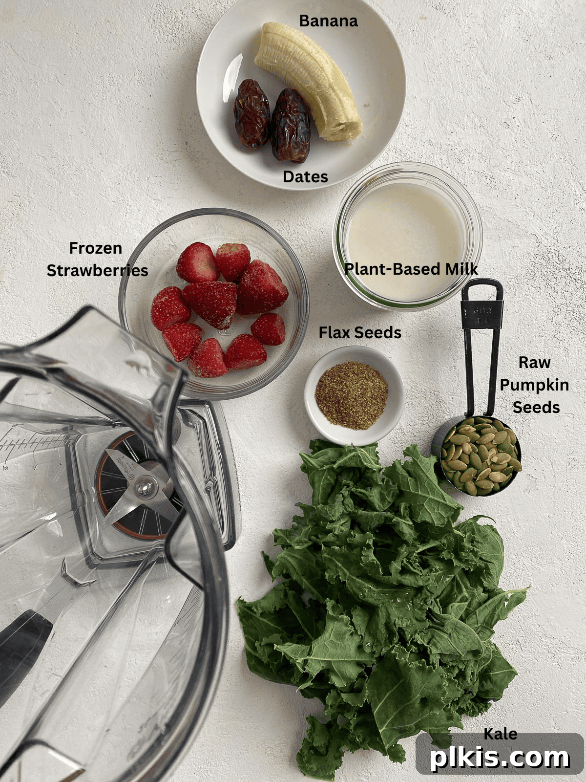 Strawberry Kale Power Elixir 3 All the fresh and raw ingredients for a Strawberry Kale Smoothie, neatly measured out and arranged on a white surface, ready for blending.