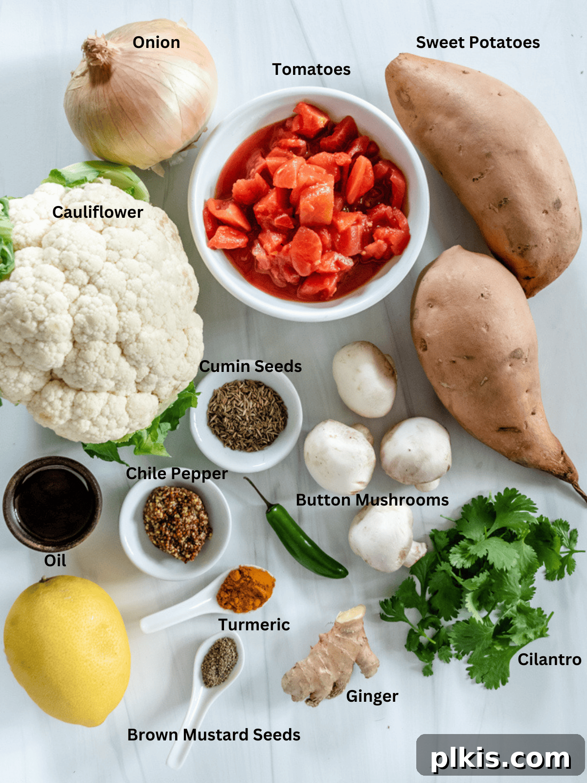 Golden Yam & Earthy Mushroom Curry with Cauliflower 3 A curated selection of fresh ingredients for Cauliflower Sweet Potato Mushroom Curry, neatly arranged on a white surface, showcasing their vibrant colors and readiness for cooking.