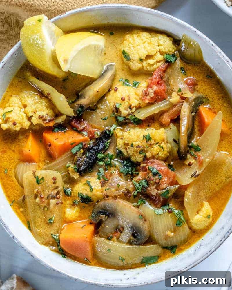 Golden Yam & Earthy Mushroom Curry with Cauliflower 4 A close-up shot of the finished Cauliflower Sweet Potato Mushroom Curry in a clean white bowl, highlighting its creamy texture and vibrant colors against a plain white background.