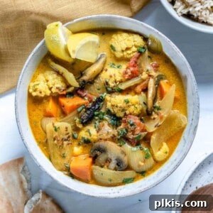 Golden Yam & Earthy Mushroom Curry with Cauliflower 6 finished Cauliflower Sweet Potato Mushroom Curry in a white bowl against a white background with ingredients in the back