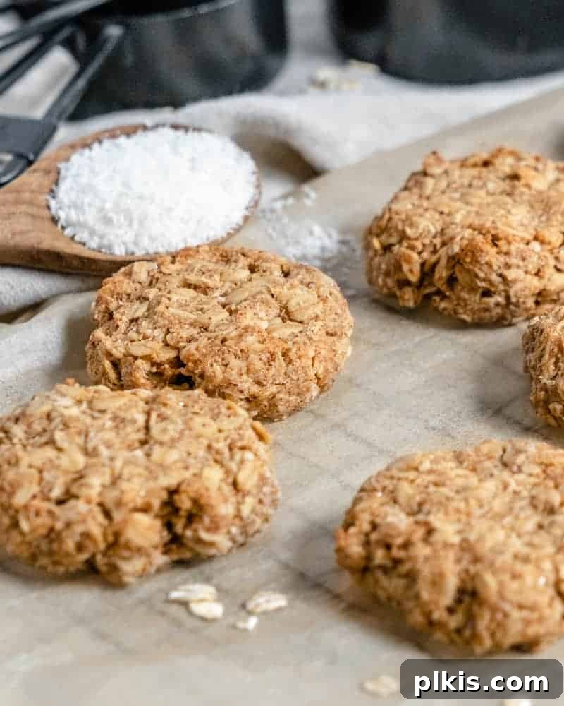 Tropical Coconut Oatmeal Treats 3 Close-up of baked Oatmeal Coconut Cookies on a grey tray, with raw ingredients blurred in the background.