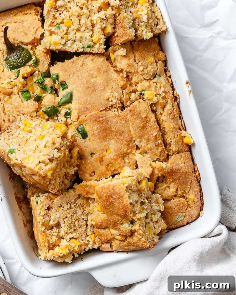 Zesty Jalapeño Cornbread 2 slices of baked jalapeno cornbread in a white baking dish.