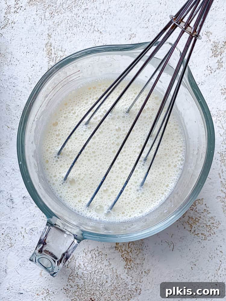 Zesty Jalapeño Cornbread 5 whisking wet ingredients for vegan jalapeno cornbread in a glass measuring cup.