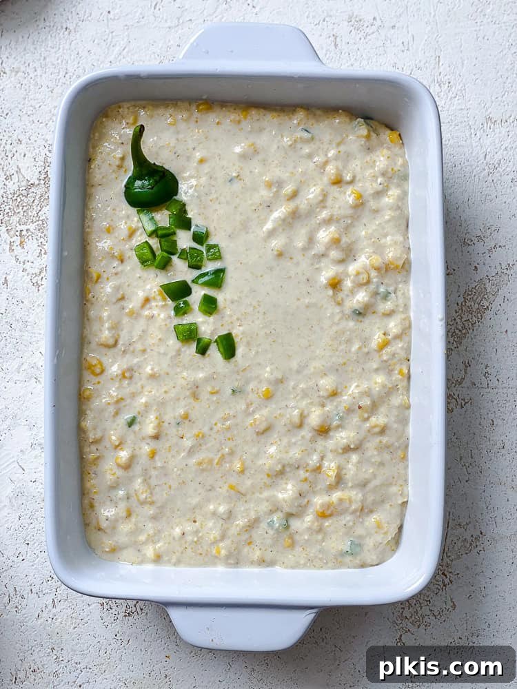 Zesty Jalapeño Cornbread 10 uncooked jalapeno cornbread batter in a white baking dish.