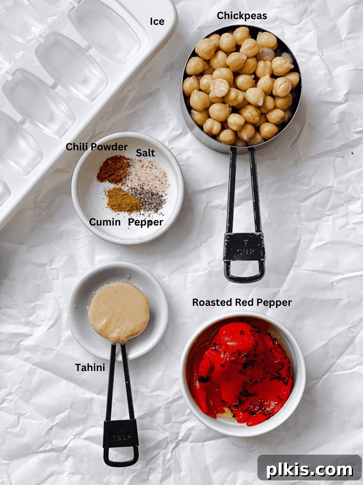 Smoky Roasted Red Pepper Hummus 3 ingredients for Roasted Red Pepper Hummus measured out on a white surface, including chickpeas, roasted red peppers, tahini, and spices