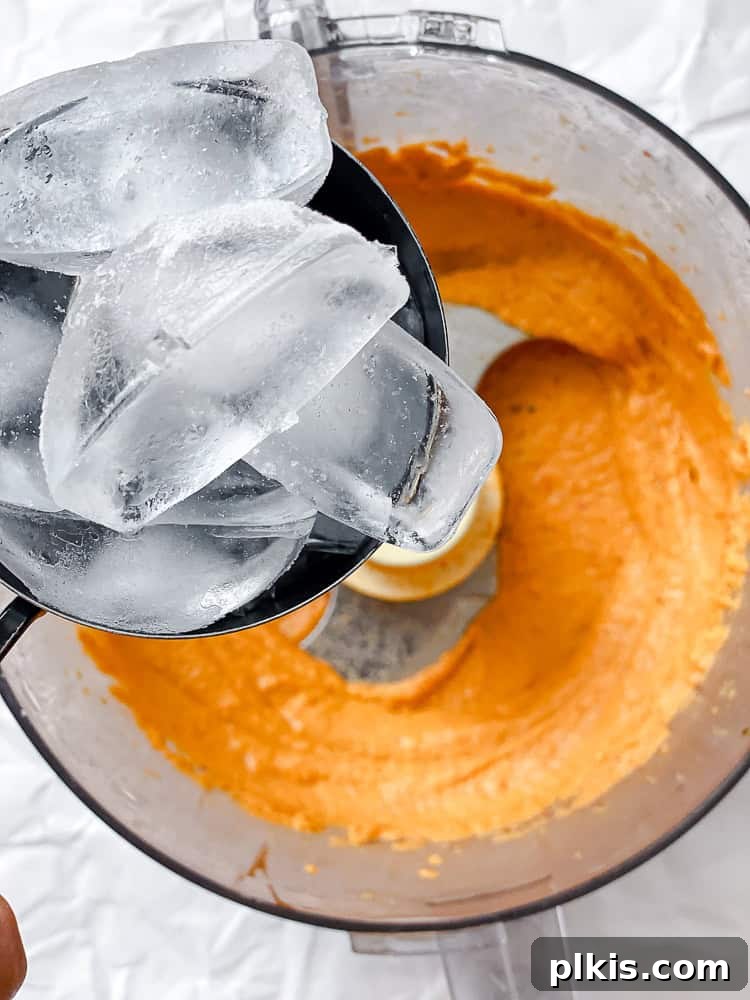 Smoky Roasted Red Pepper Hummus 5 process shot showing adding ice to food processor for extra creamy hummus