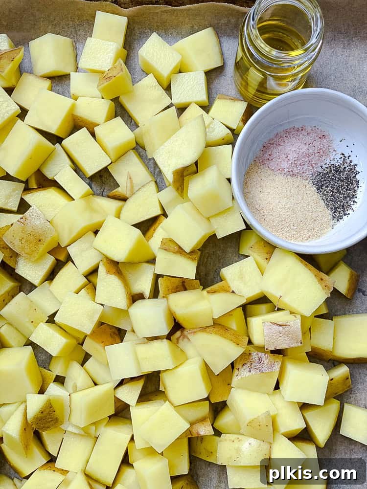 Process shot showing evenly diced potatoes spread in a single layer on a baking dish, ready for roasting